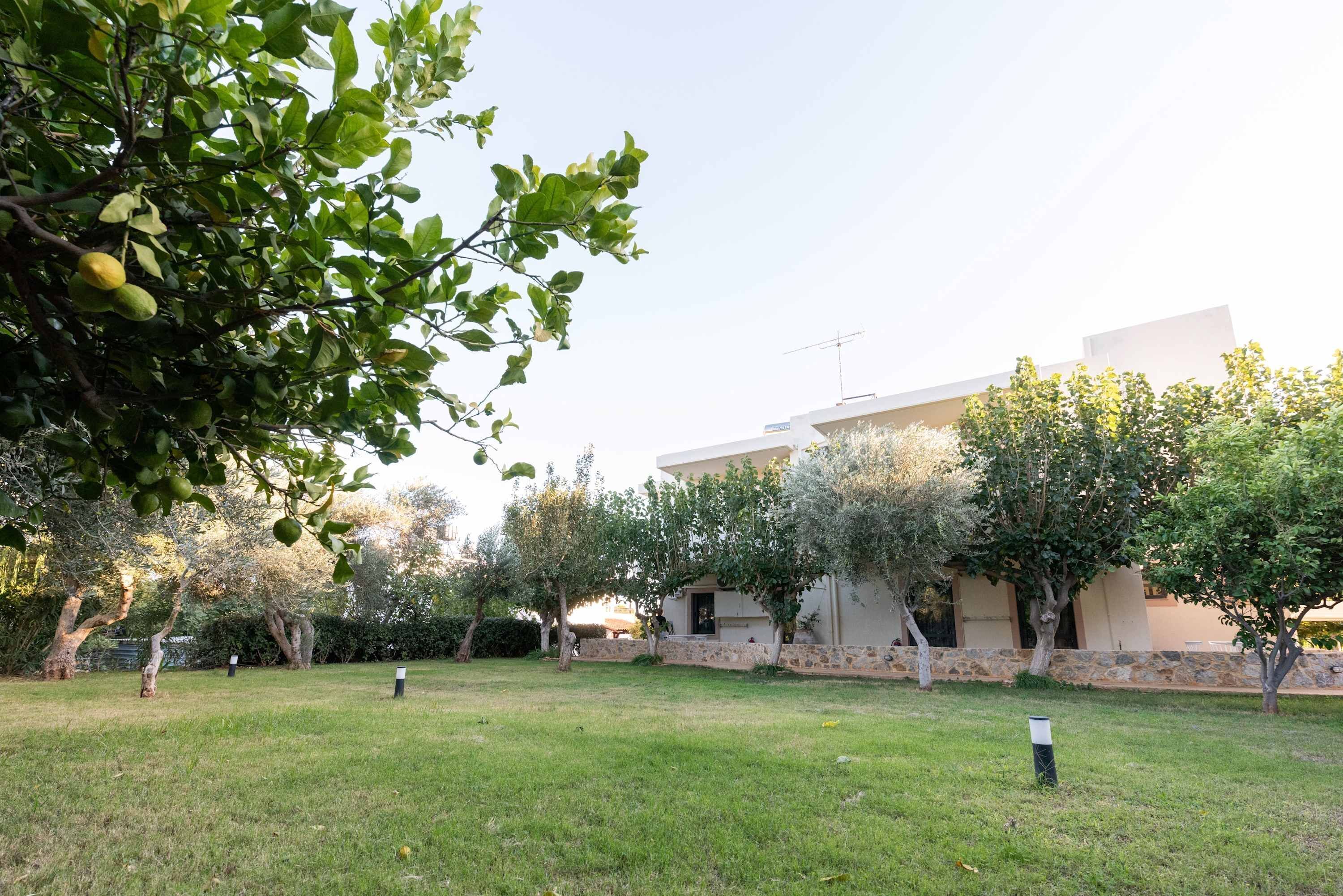 A modern building with a stone facade, surrounded by a grassy lawn and trees.