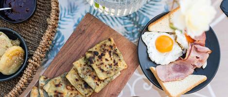 A breakfast setting with toast, eggs, ham, and flatbreads on a wooden board.