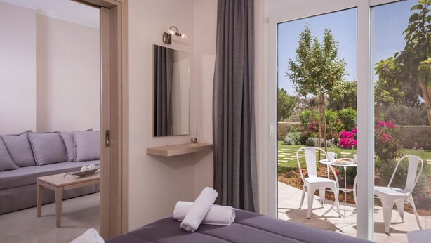 Une chambre moderne comprenant un lit, un canapé, une petite table et un balcon avec des chaises et une table.