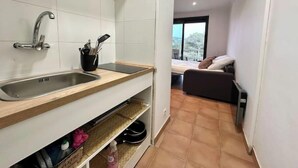 A compact kitchen with a sink, countertop, and storage shelves.