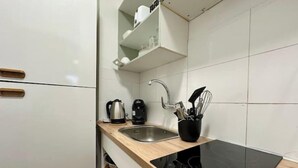 A modern kitchen with a black induction cooktop, a stainless steel sink, and a coffee maker.