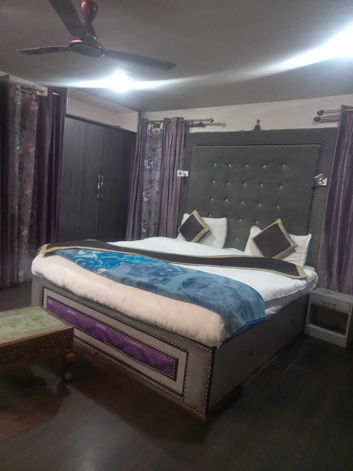 A bedroom with a bed, a nightstand, a ceiling fan, and a wardrobe.