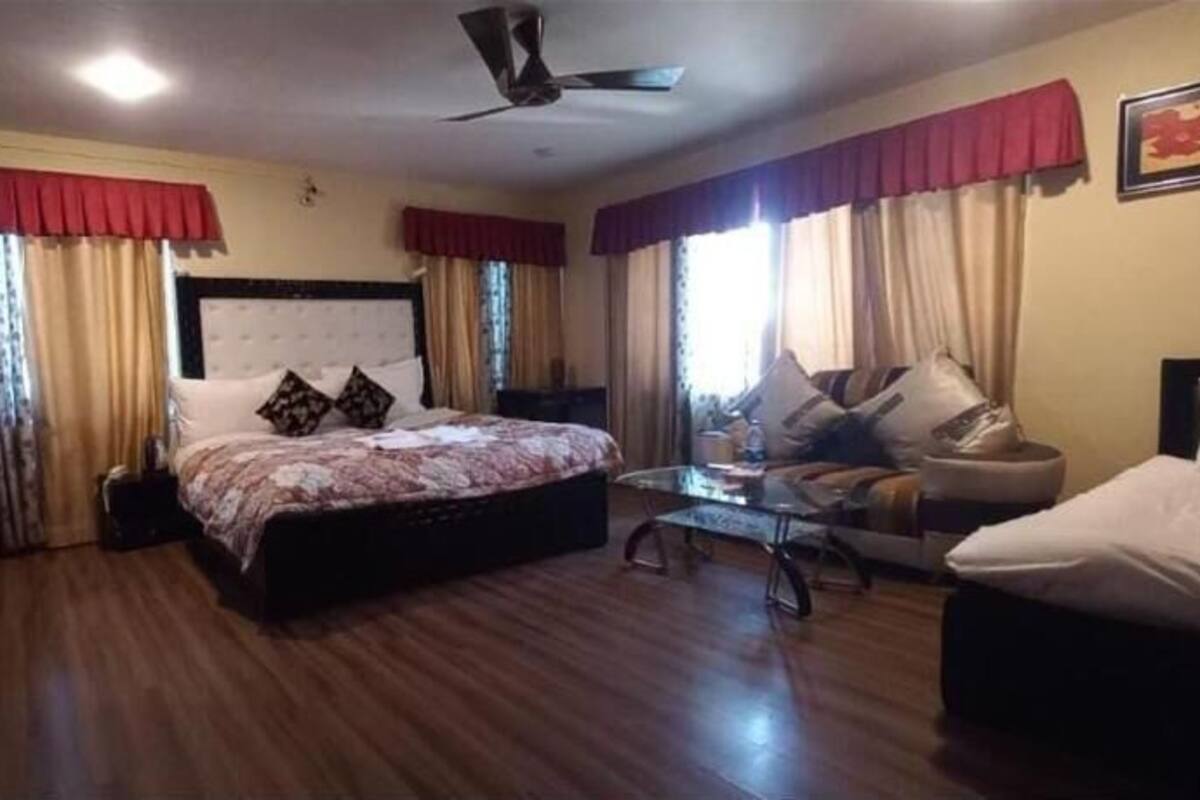 A bedroom with a large bed, a sofa, a small table, and a wardrobe.