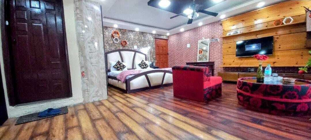 A bedroom with a bed, a red chair, a TV, and a wooden wall.