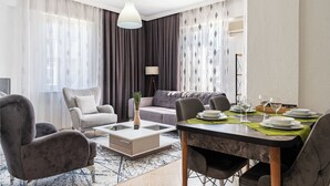 Un salon moderne avec un coin repas, comprenant un canapé, des fauteuils, une table basse et une table à manger pour quatre personnes.