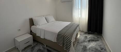 Un dormitorio moderno con una cama, una mesita de noche y una alfombra estampada.