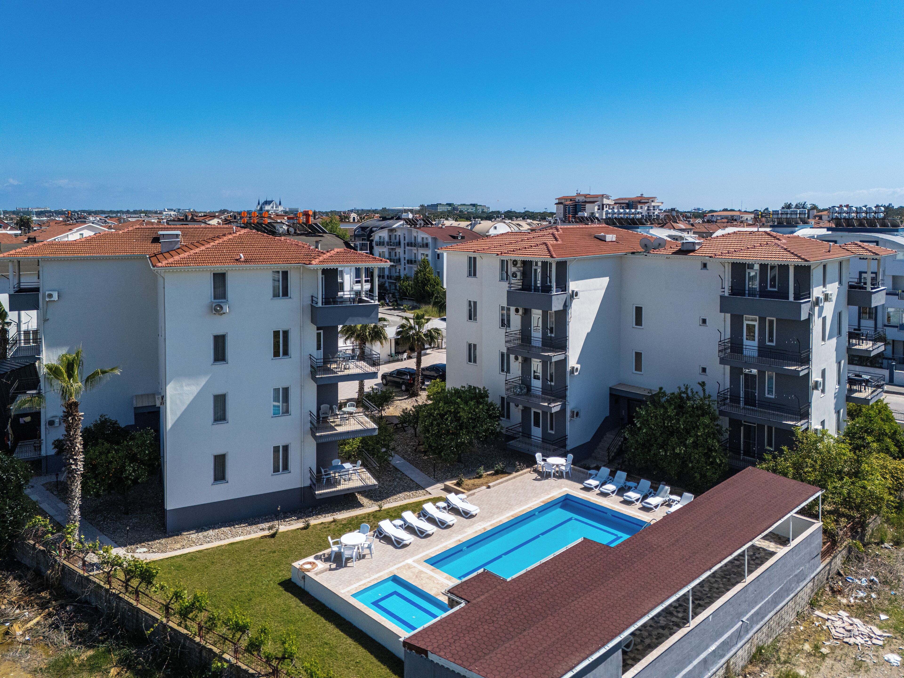 Un moderno complejo de apartamentos con piscina, varios balcones y vistas de la ciudad circundante.