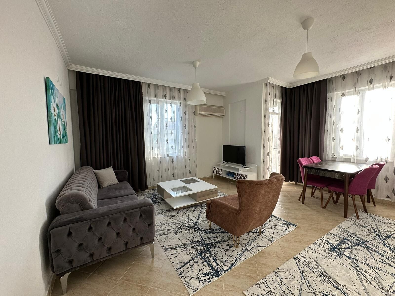 A modern living room with a sofa, a coffee table, a TV stand, and a dining area with a table and chairs.