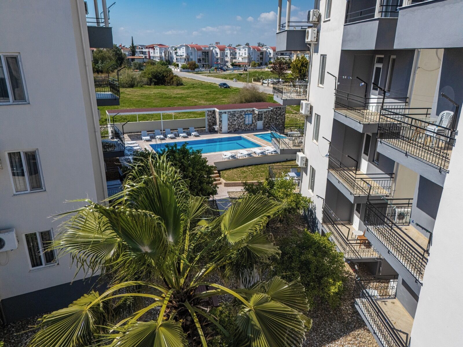 A residential building with a swimming pool, balconies, and a view of the surrounding area.