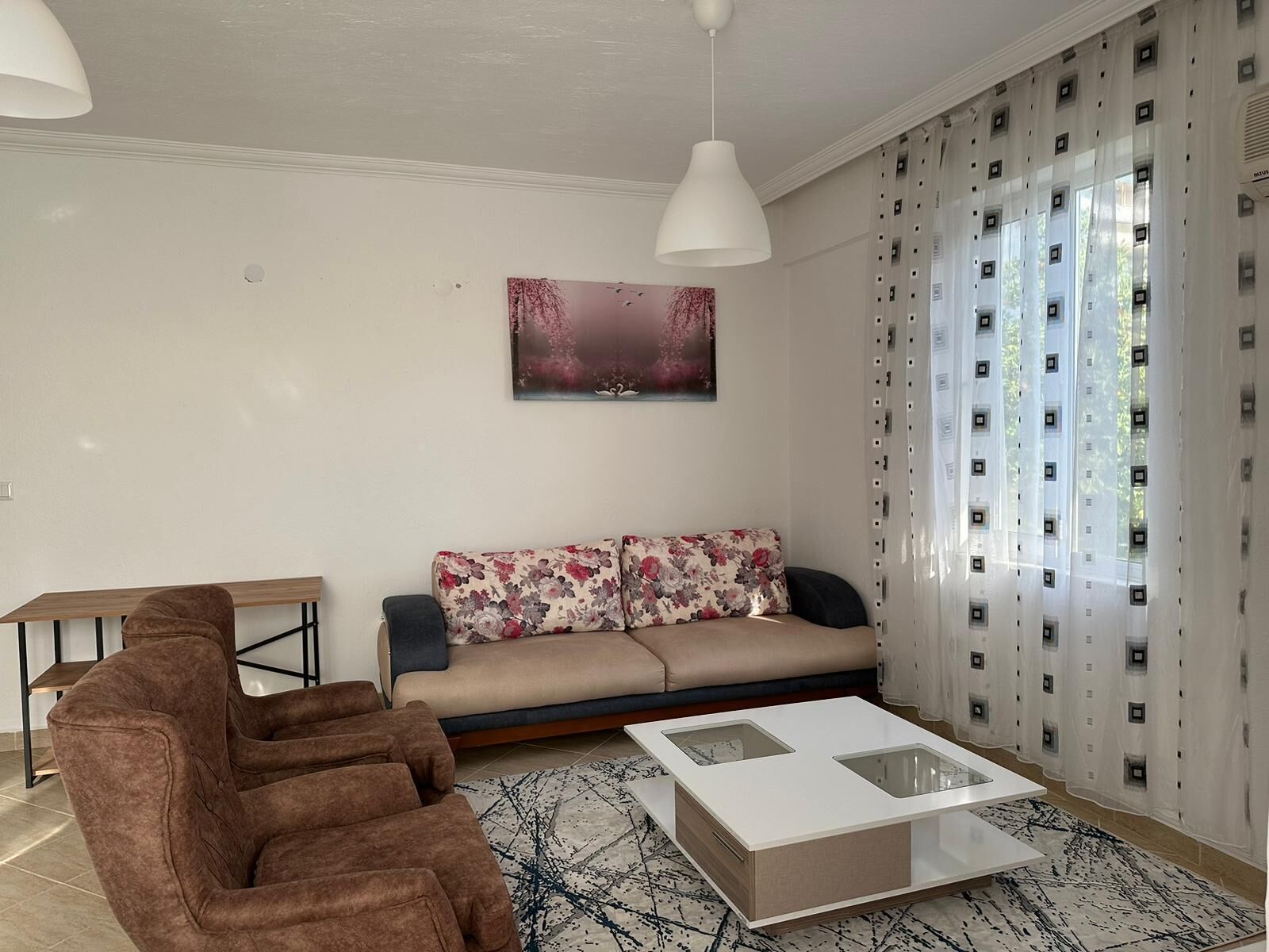 A modern living room with a sofa, two armchairs, a coffee table, and a painting on the wall.