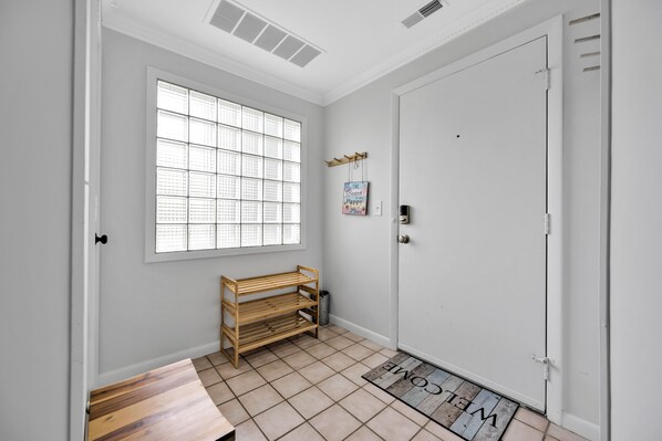 Ein Zimmer mit großem Fenster, einer hölzernen Bank, einer Tür und einer Fußmatte.