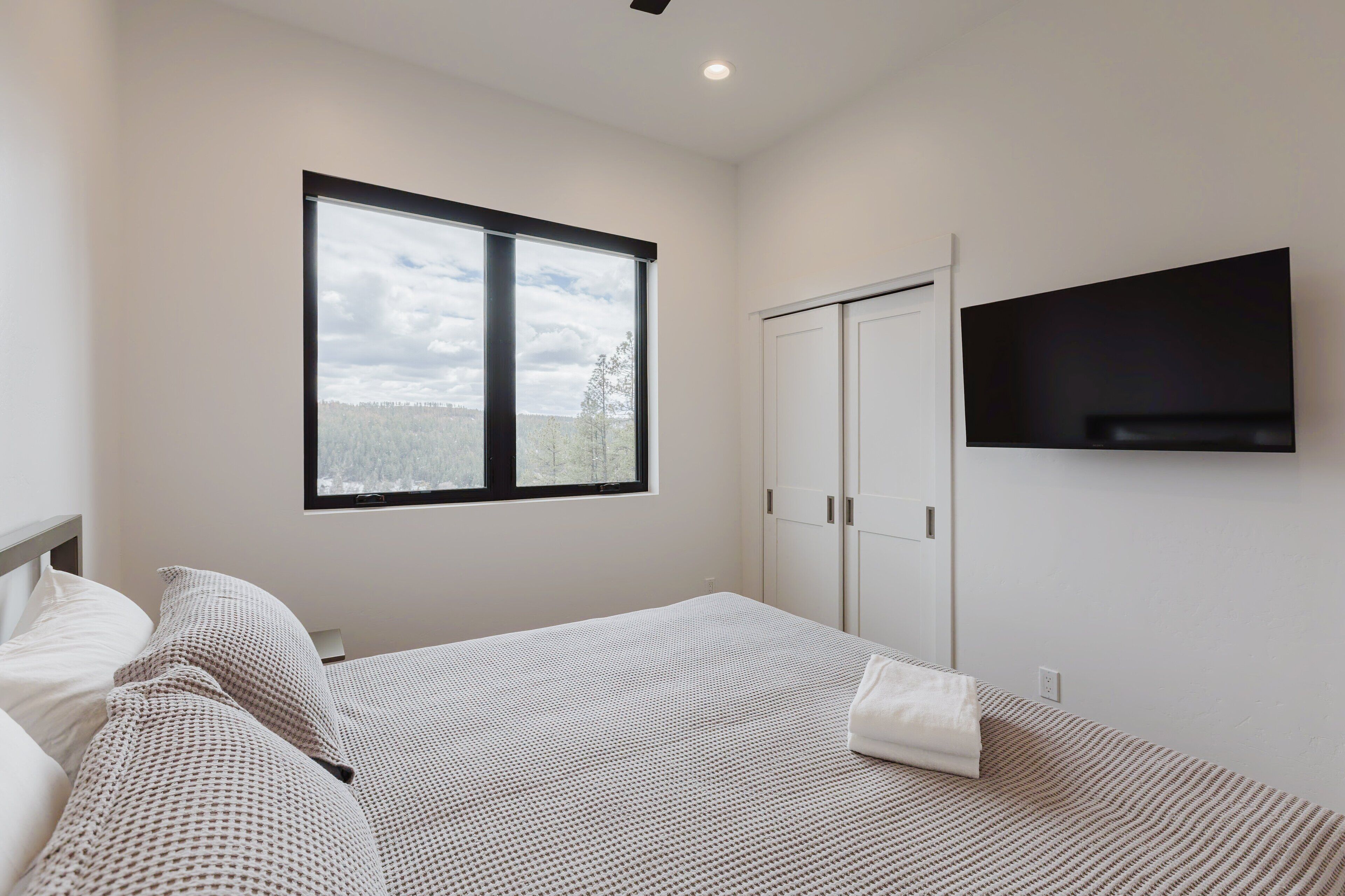 Une chambre à coucher avec un lit, une fenêtre, une armoire et un téléviseur.