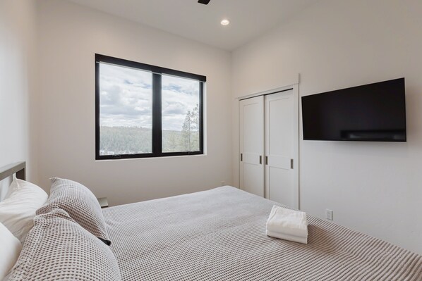 A bedroom with a bed, a window, a wardrobe, and a TV.