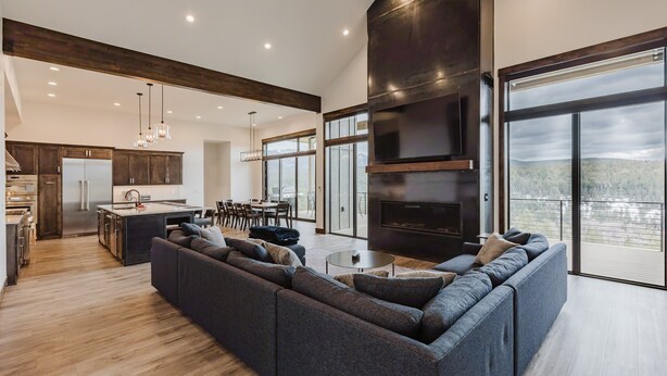 A modern kitchen with a large island, dark wood accents, and a dining area with a view. - Luxury Listing | A/C, Hot Tub, Close to Skiing, Incredible Mountain Views (Pagosa Springs)
