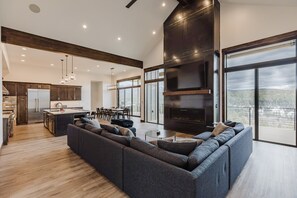 A modern kitchen with a large island, dark wood accents, and a dining area with a view.