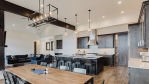 A modern kitchen with a central island, dark cabinetry, and pendant lighting. - Luxury Listing | A/C, Hot Tub, Close to Skiing, Incredible Mountain Views (Pagosa Springs)