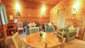 A cozy cabin interior with a wooden dining table, two sofas, and a wooden chair.