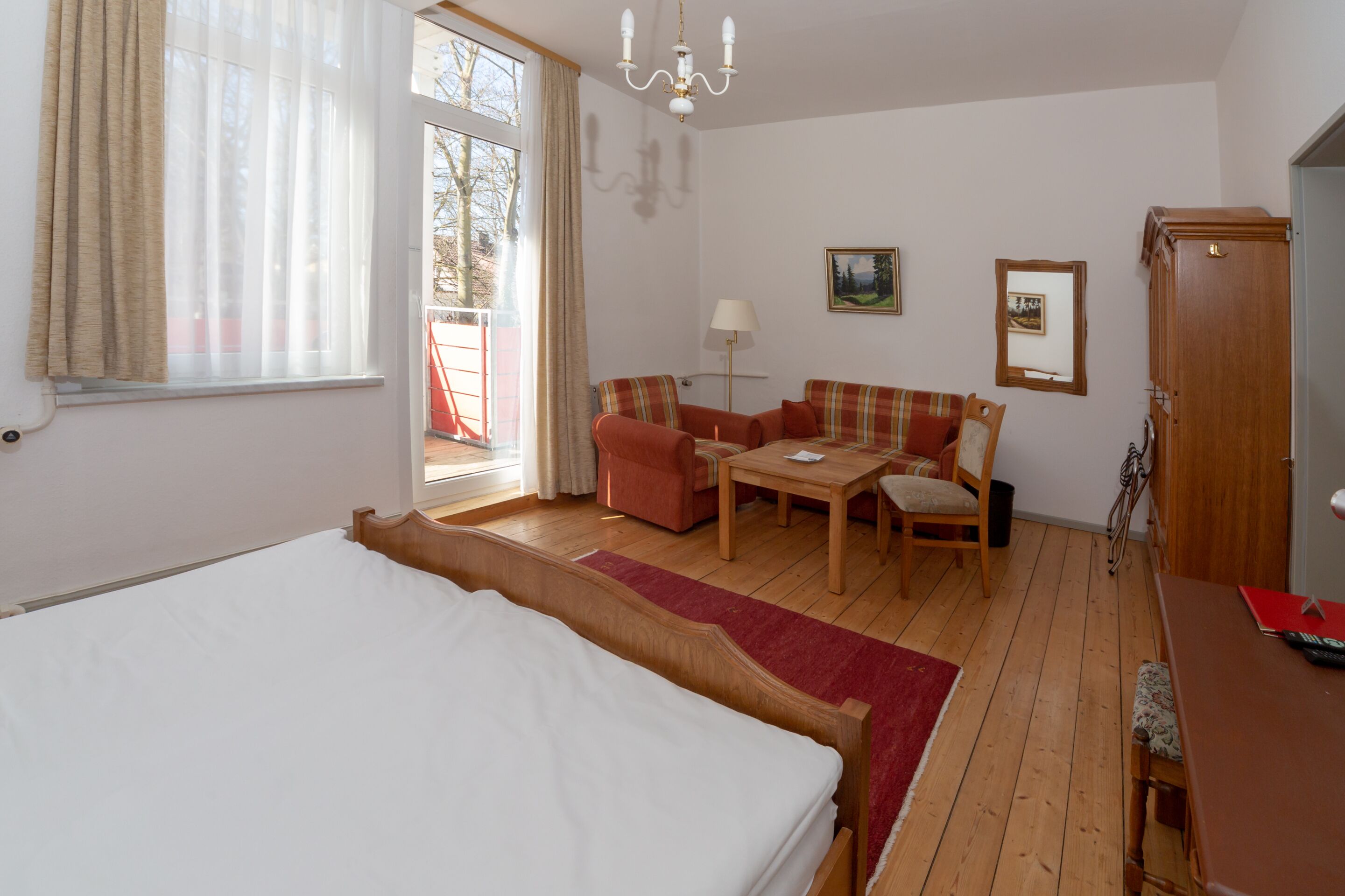 A bedroom with a large bed, a sofa, a small table, and a cabinet.