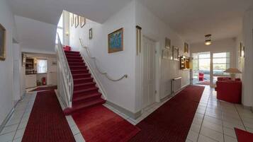A spacious hallway with a red carpet leading to a staircase.