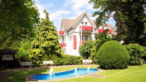 A hotel with a swimming pool, surrounded by lush greenery and a well-maintained lawn. - Villa Feise (Bad Harzburg)