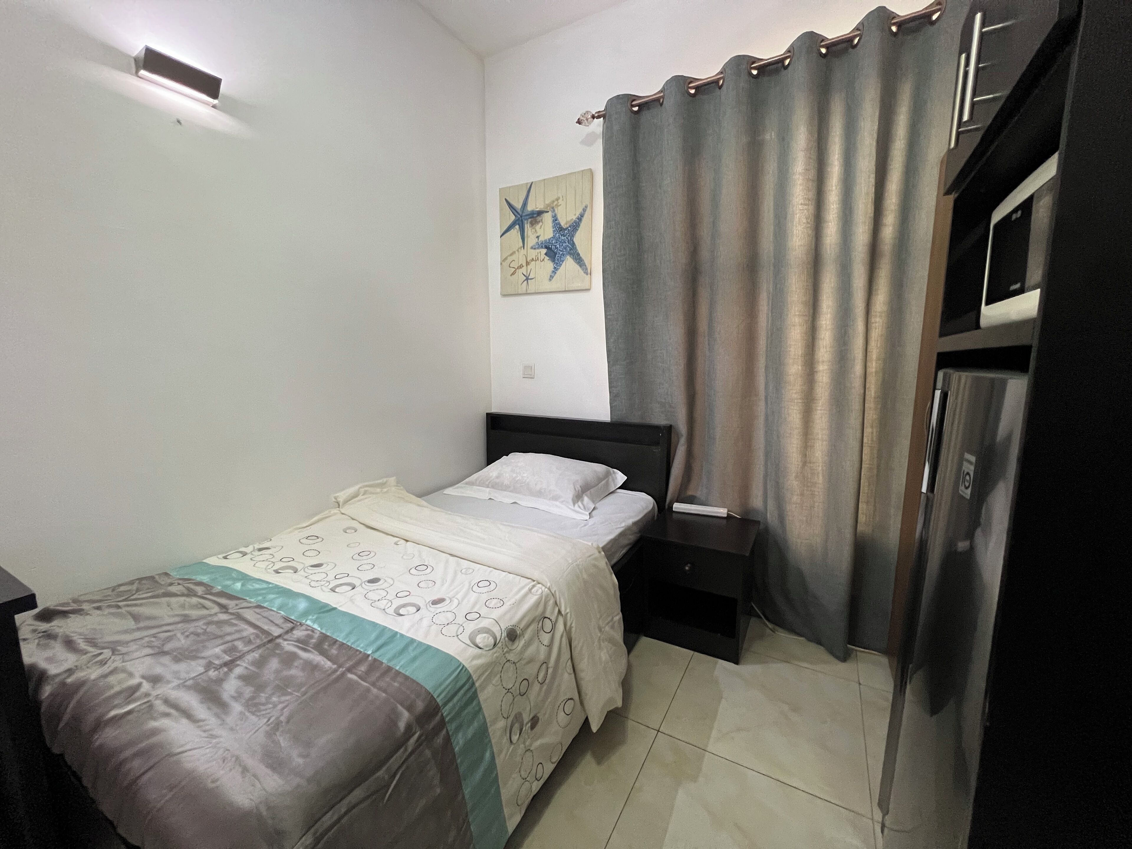 Un dormitorio pequeño y ordenado con cama, mesita de noche y un adorno de estrella en la pared.