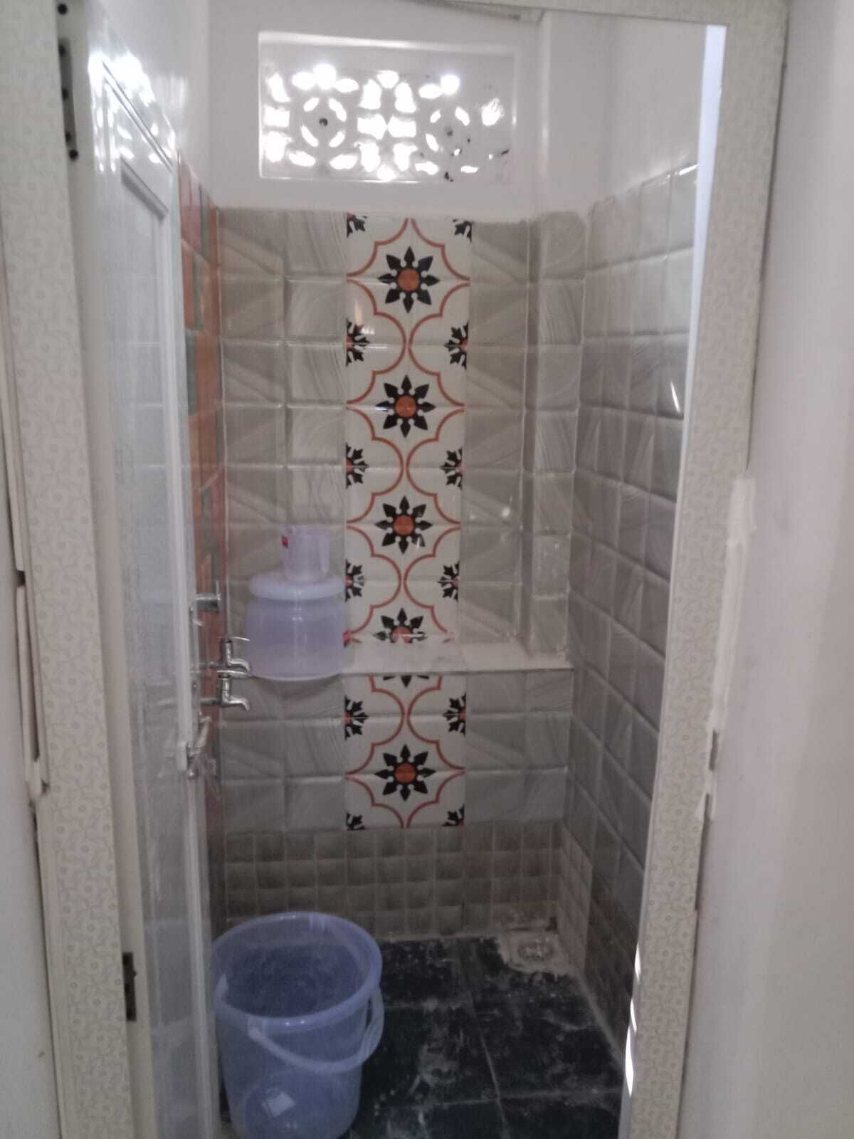 A small bathroom with tiled walls, a shower area, and a toilet.