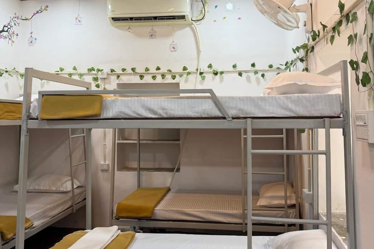 Habitación con literas, ropa de cama blanca, techo de madera y aire acondicionado.