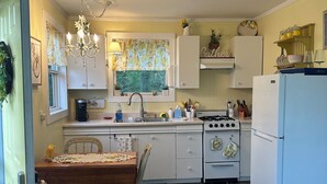 A kitchen with a dining table, chairs, a chandelier, a stove, and a refrigerator.