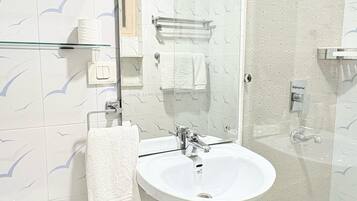 A bathroom with a white sink, a glass shower enclosure, and a mirror above the sink.