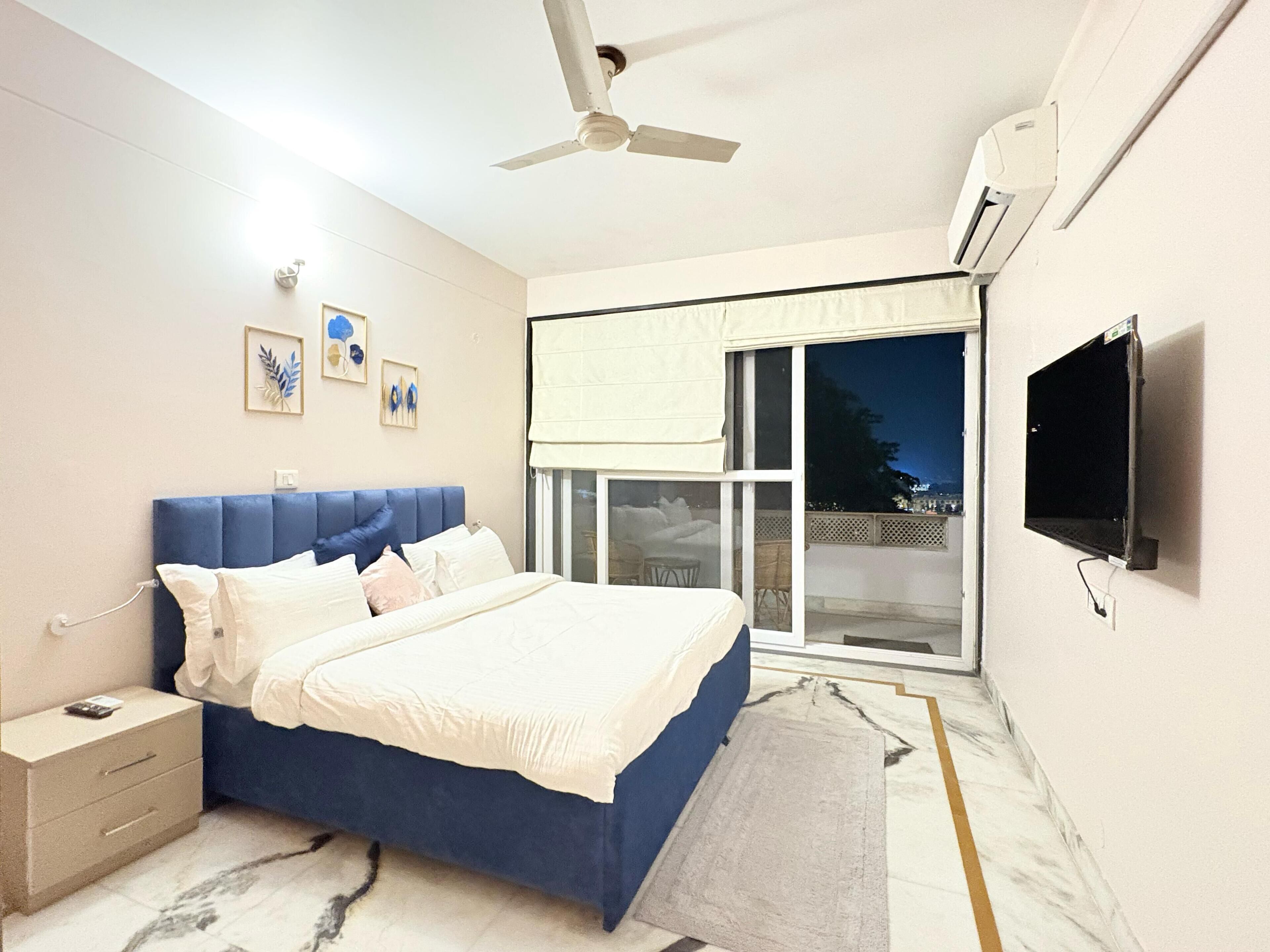 A bedroom with a bed, nightstand, and a TV mounted on the wall.