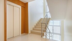 Un interior moderno con una escalera, un panel de pared de madera y una puerta blanca.