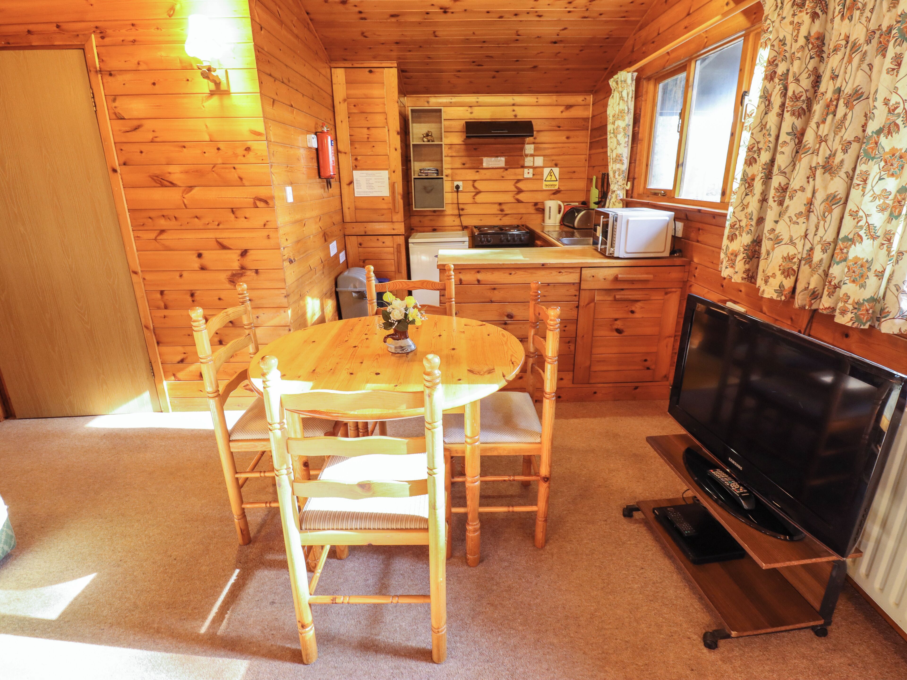 Ein Holzblockhaus-Interieur mit Essbereich, Küche und Fernseher.
