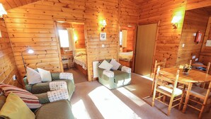 A cozy cabin interior with a sofa, a small table, and a bed.