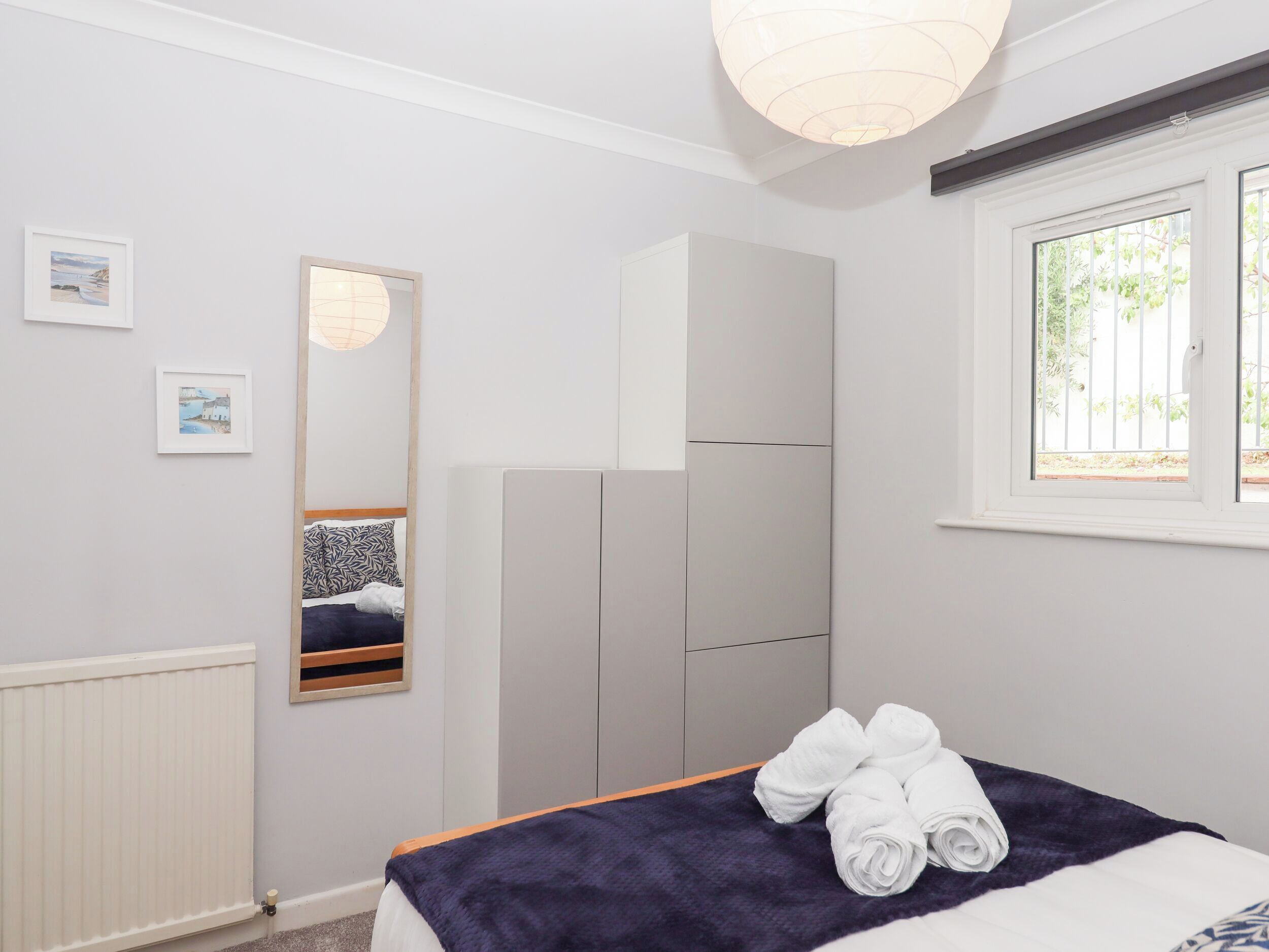 A bedroom with a bed, a wardrobe, a mirror, and a window.