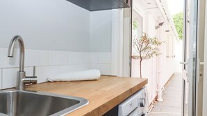 A modern kitchen with a stainless steel sink, wooden countertop, and a built-in washing machine. - 15 Summerland Avenue (Dawlish)