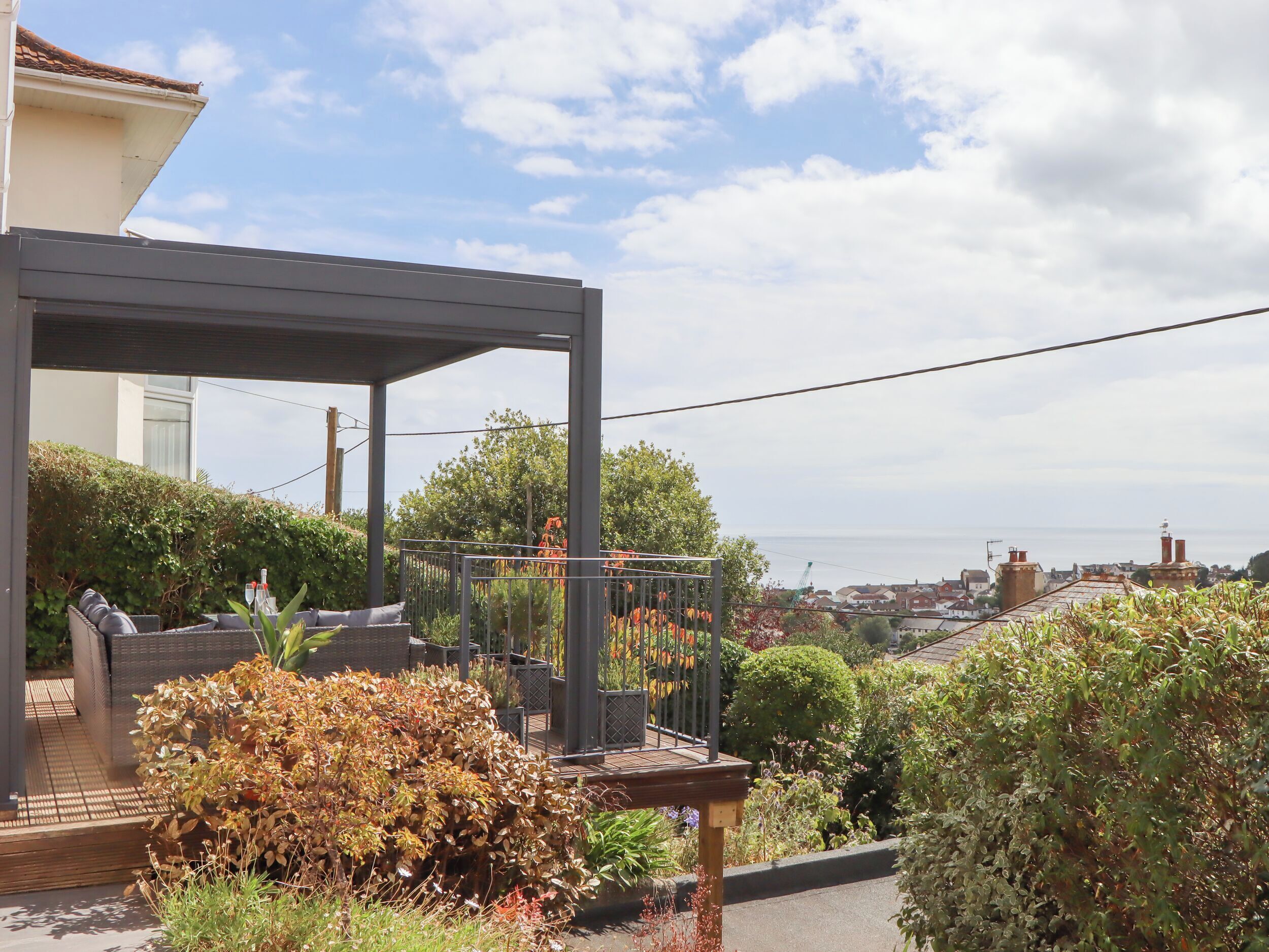 A rooftop garden with a pergola, various plants, and a view of the cityscape.