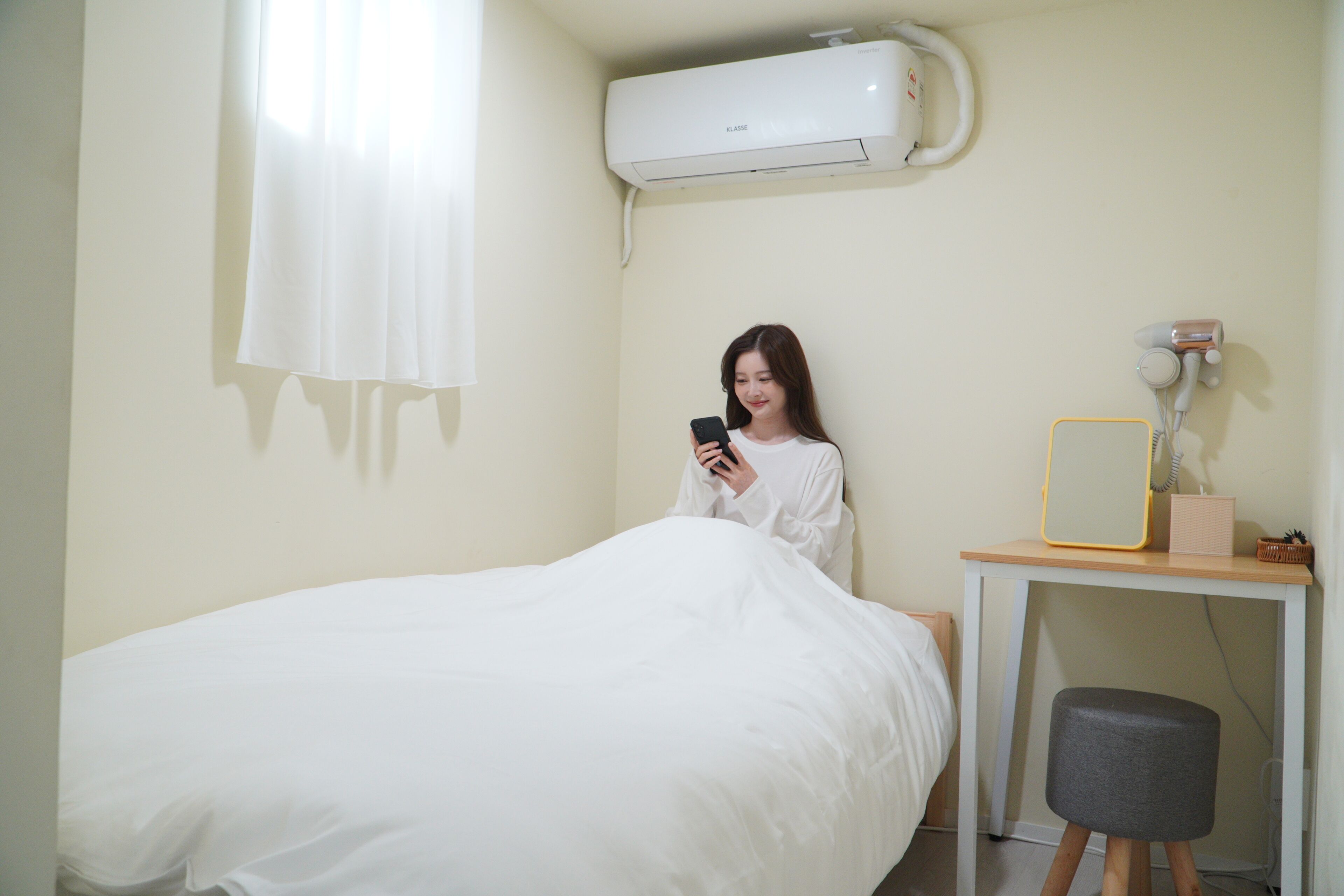 A room with a bed, a small table with a mirror, and an air conditioner on the wall.