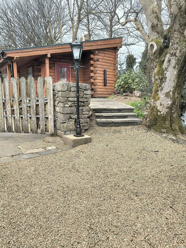 Une cabane rustique en rondins de bois, avec un mur en pierre et une clôture en bois.