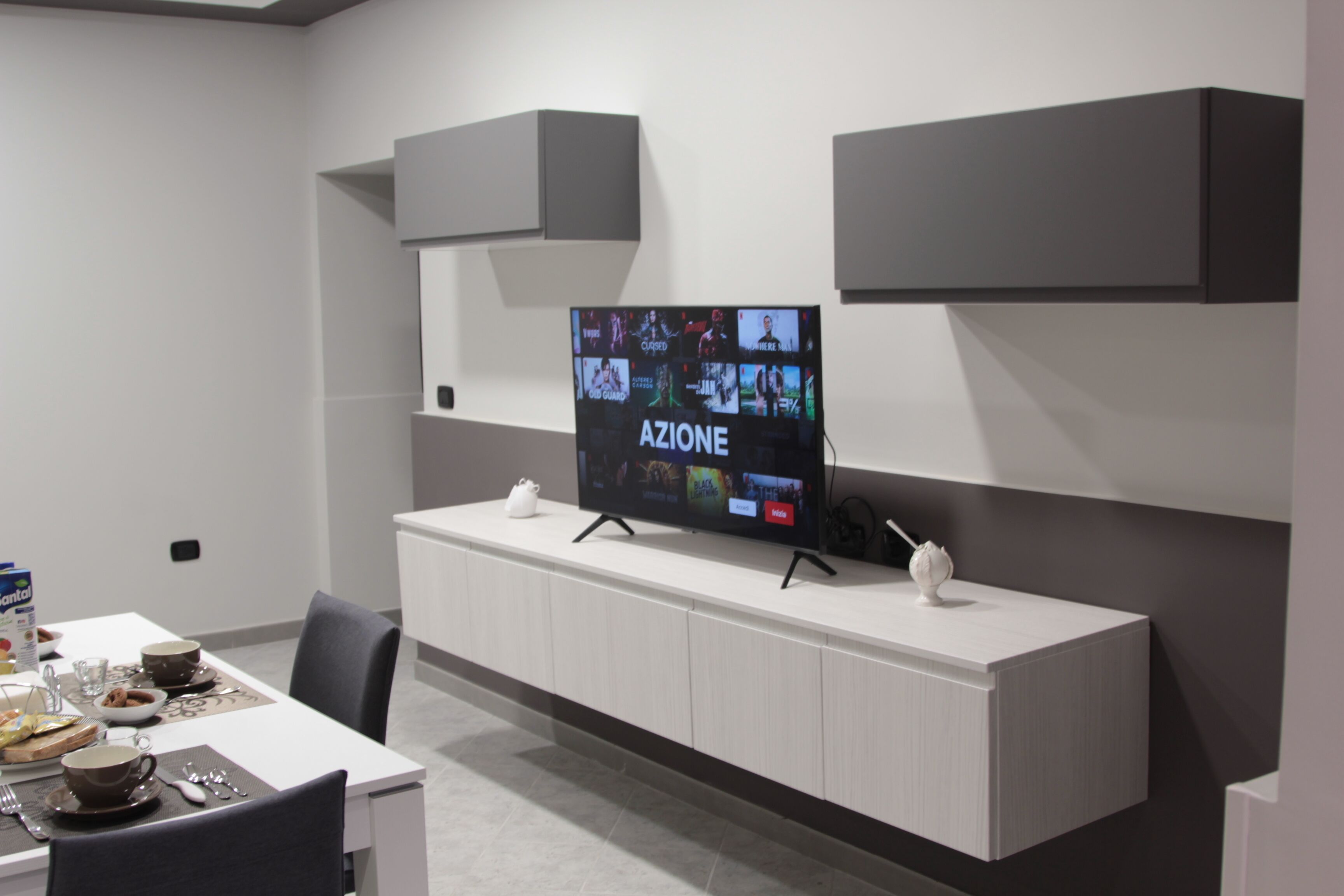 Un comedor moderno con un televisor de pantalla plana mostrando 'AZIONE'.