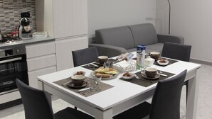 A modern kitchen with a dining area. It includes a coffee maker, a toaster, and a microwave. There is a dining table with chairs and a sofa. - AGAS Exclusive Apartment (Catanzaro)