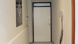 A hallway with a door, a coat rack, and a sign on the wall. - AGAS Exclusive Apartment (Catanzaro)