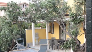A patio with a hammock, dining table, chairs, and a yellow wall. - AGAS Exclusive Apartment (Catanzaro)