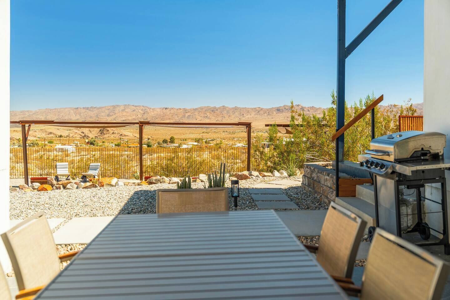 Un patio al aire libre con vistas a montañas, una parrilla y asientos.