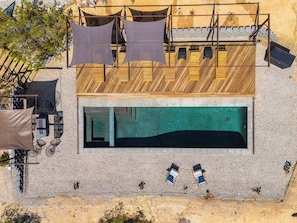 A modern building with a swimming pool, outdoor seating, and a covered area with hanging cloths. - Casa Azul | Joshua Tree | Swim | Relax | Recharge (Joshua Tree)