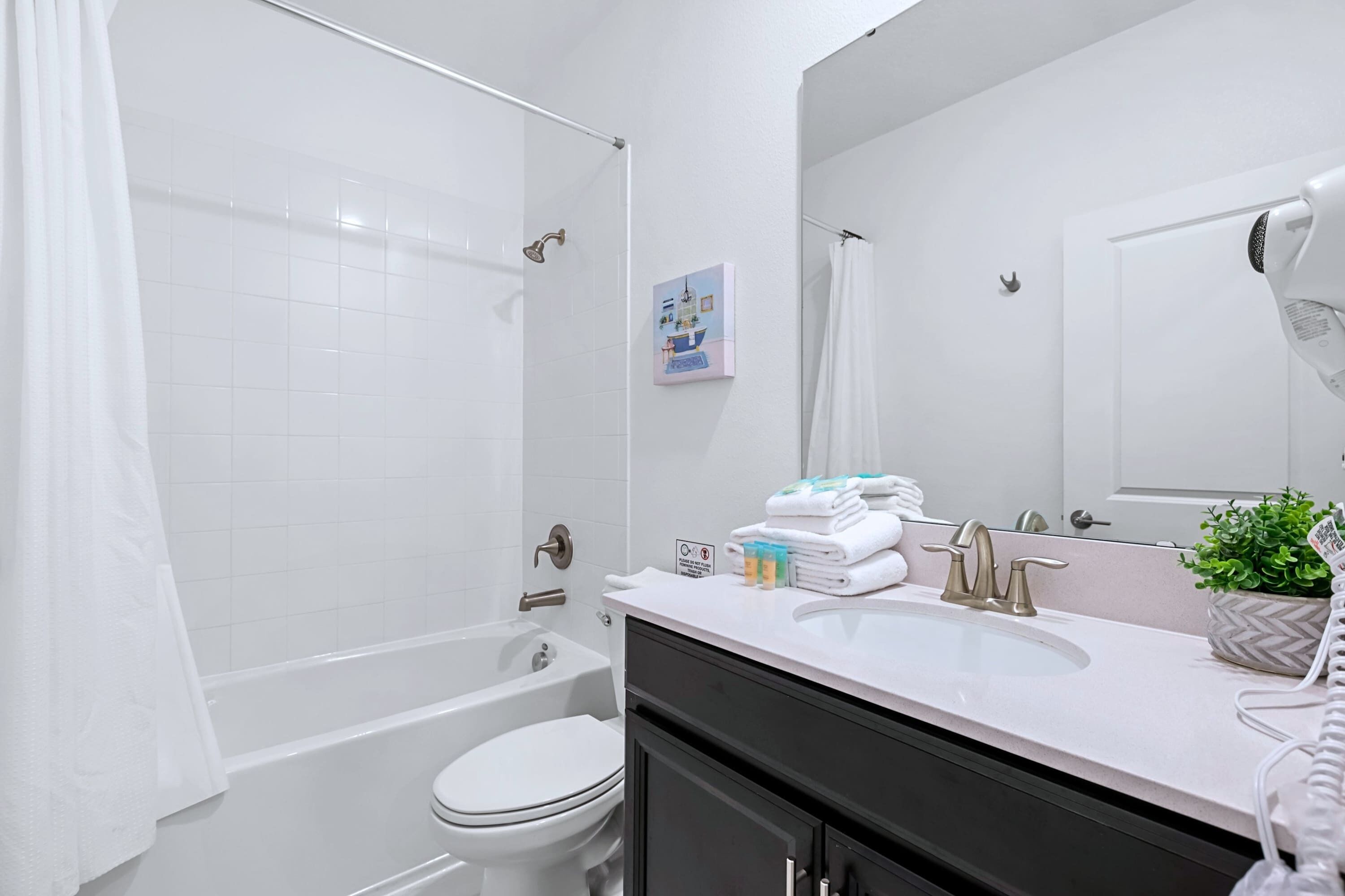 A bathroom with a bathtub, toilet, sink, and a mirror.