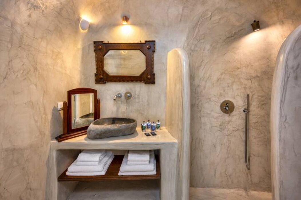 A bathroom with a stone sink, a mirror, and a shower.