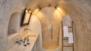 A bathroom with a marble sink, a mirror, a shower, and a towel rack.