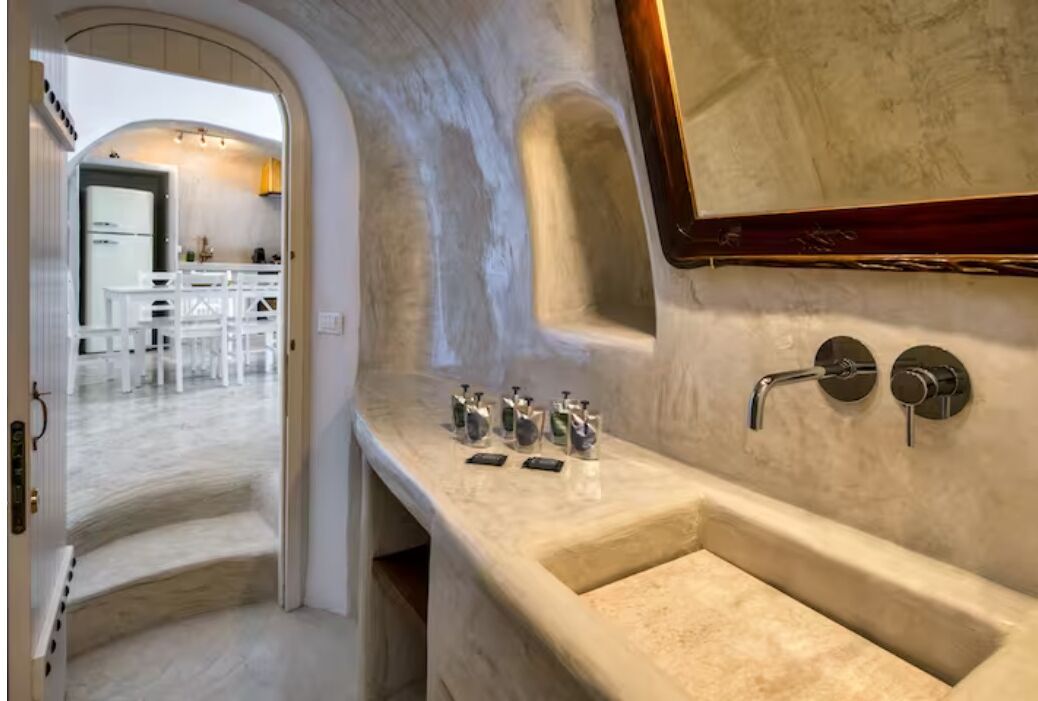 A modern bathroom with a large sink, a mirror, and a shower area.