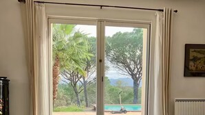 A spacious room with a large sliding glass door leading to an outdoor area with a pool and trees.