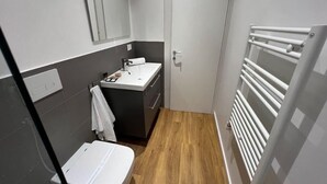 A compact bathroom with a toilet, sink, and mirror.